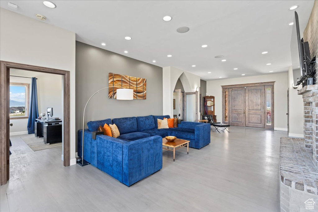 Living room with arched walkways, recessed lighting, and light wood-style flooring