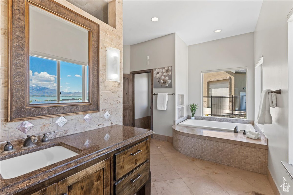 Bathroom featuring vanity, tasteful backsplash, a garden tub, and tile patterned floors