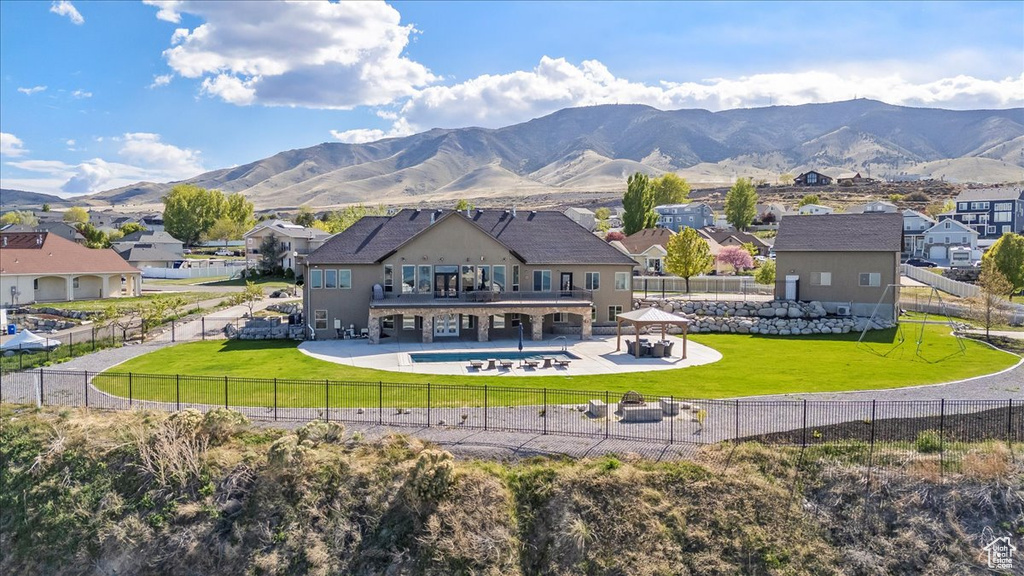 Rear view of house with a residential view, a patio area, a mountain view, a fenced backyard, and a yard