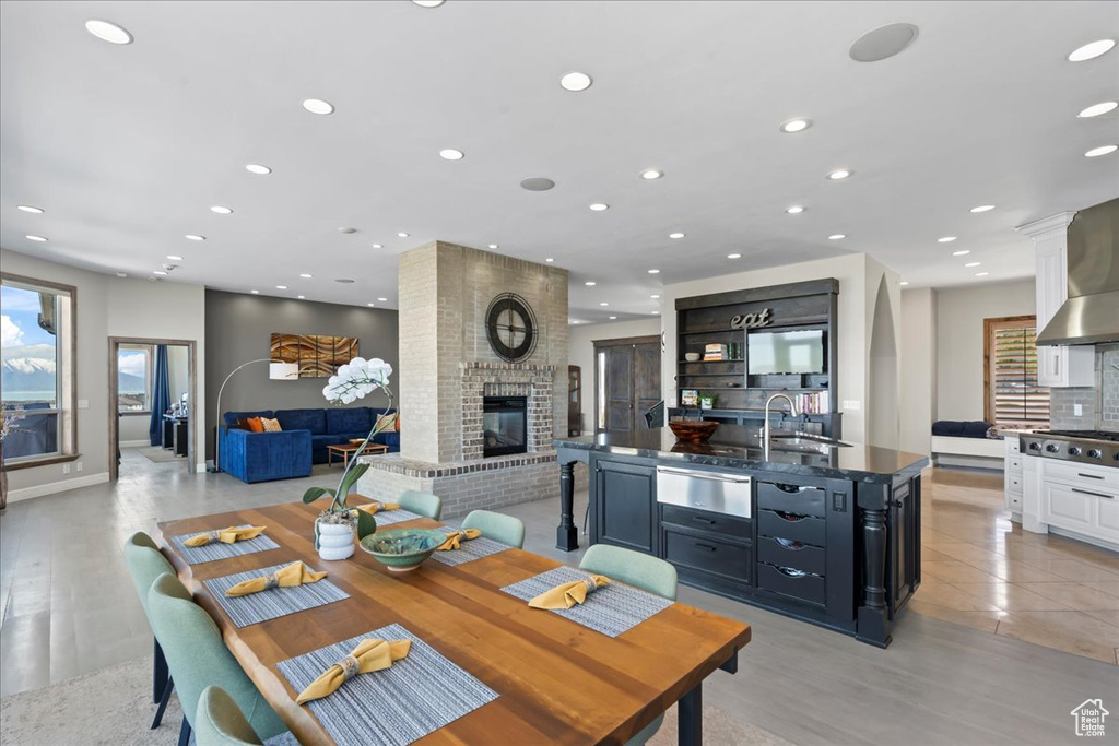 Dining area featuring light wood-type flooring, a brick fireplace, and recessed lighting