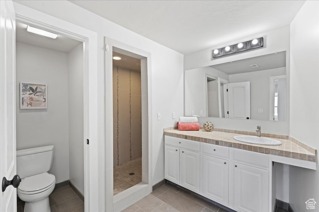 Full bath with vanity, tile patterned floors, toilet, and a shower stall