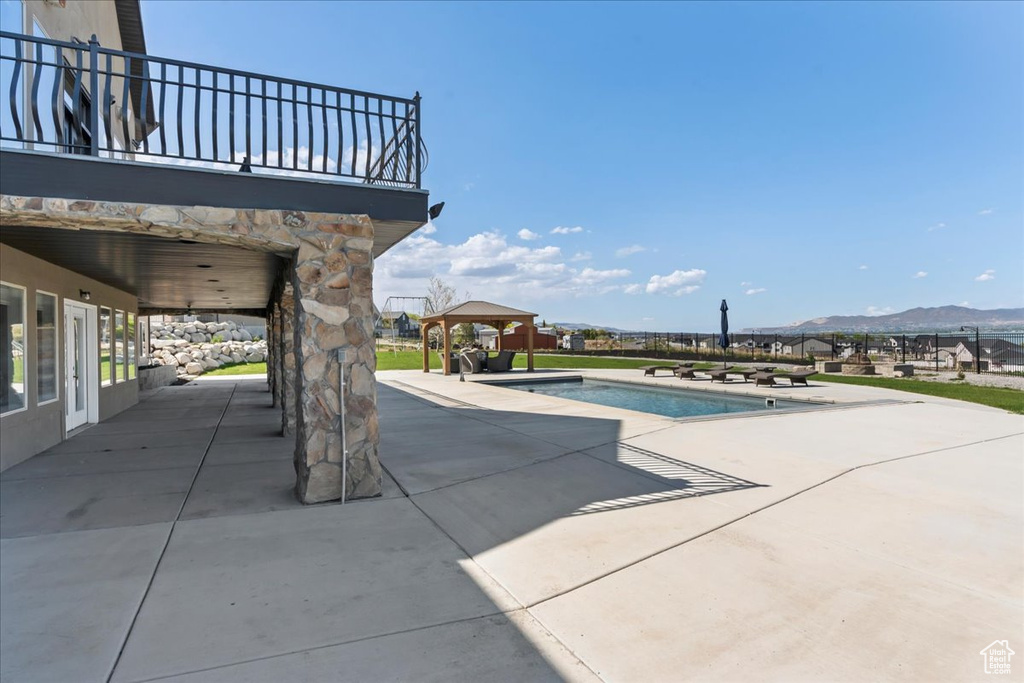 Outdoor pool with a mountain view, a gazebo, and a patio area