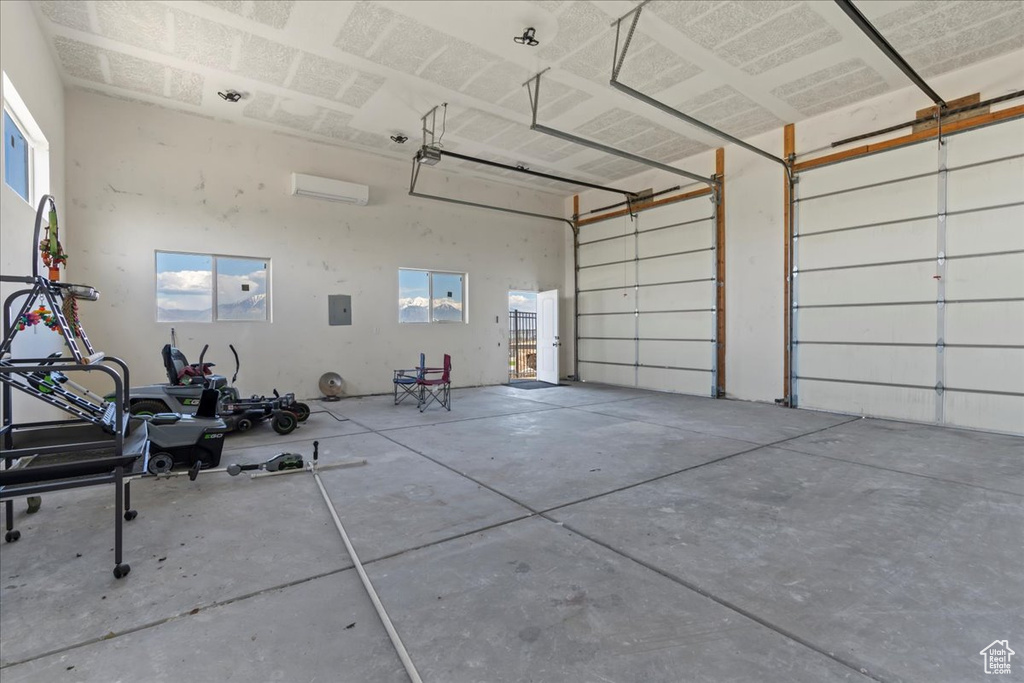 Garage featuring a wall mounted air conditioner and electric panel