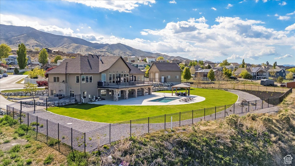 Back of property with a gazebo, a fenced backyard, a lawn, and a residential view
