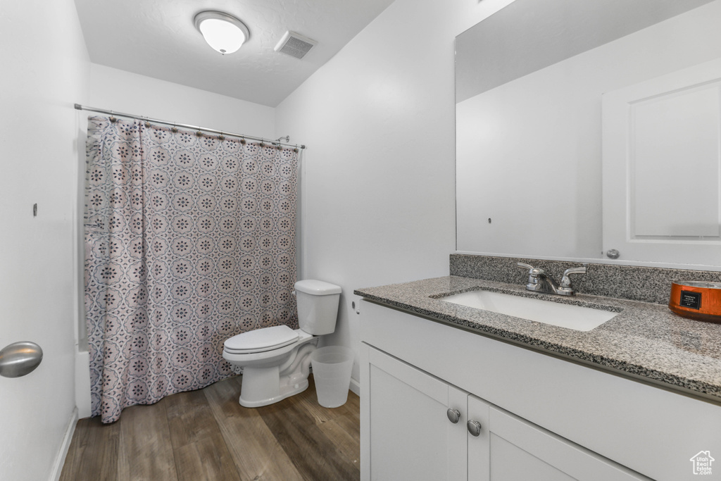 Full bath featuring vanity, toilet, baseboards, wood finished floors, and visible vents