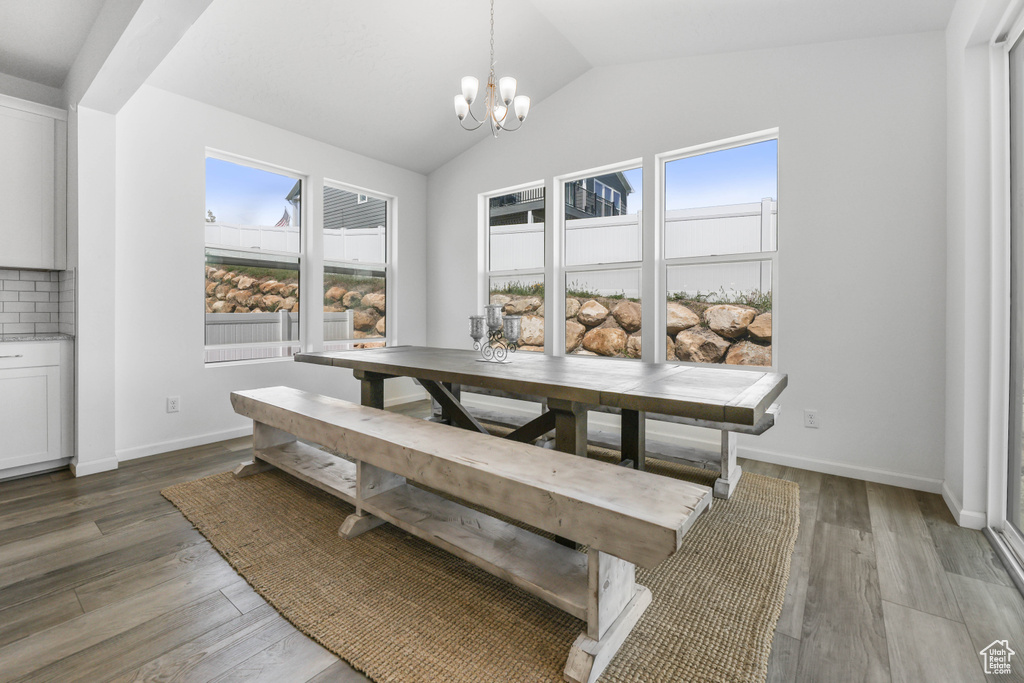Dining space with light wood-style floors, a wealth of natural light, vaulted ceiling, and a notable chandelier