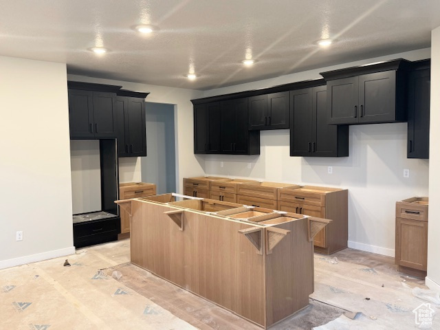 Kitchen featuring baseboards, dark cabinets, and a center island
