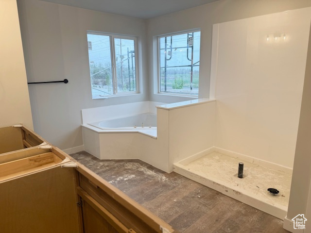 Full bath with a garden tub and baseboards