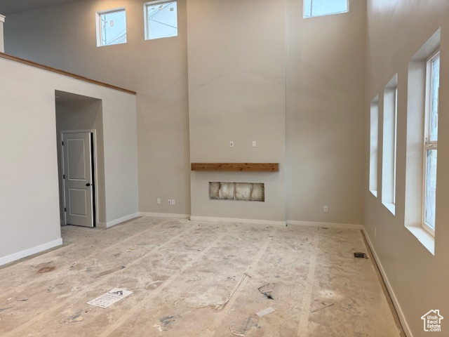 Unfurnished living room featuring a healthy amount of sunlight, visible vents, and a high ceiling