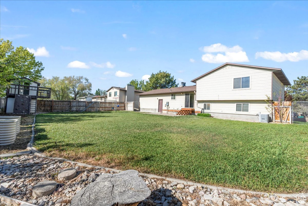 Rear view of house with a fenced backyard and a lawn