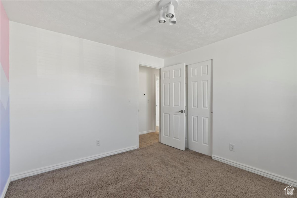 Unfurnished bedroom featuring a closet, carpet flooring, baseboards, and a textured ceiling