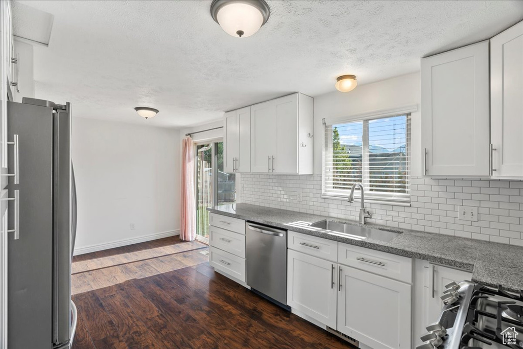 Kitchen featuring a sink, decorative backsplash, appliances with stainless steel finishes, and white cabinets