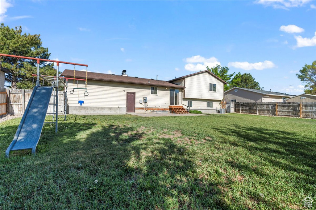 Back of house featuring a lawn, entry steps, and a fenced backyard