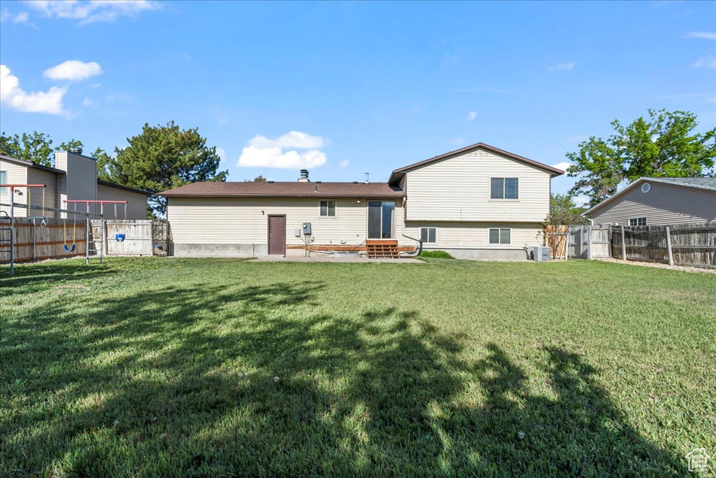 Back of property with a lawn, a fenced backyard, and entry steps