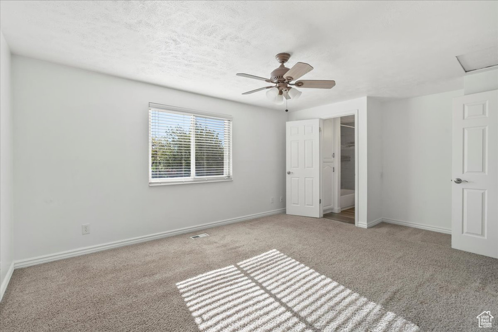 Unfurnished bedroom with baseboards, carpet, ceiling fan, and visible vents