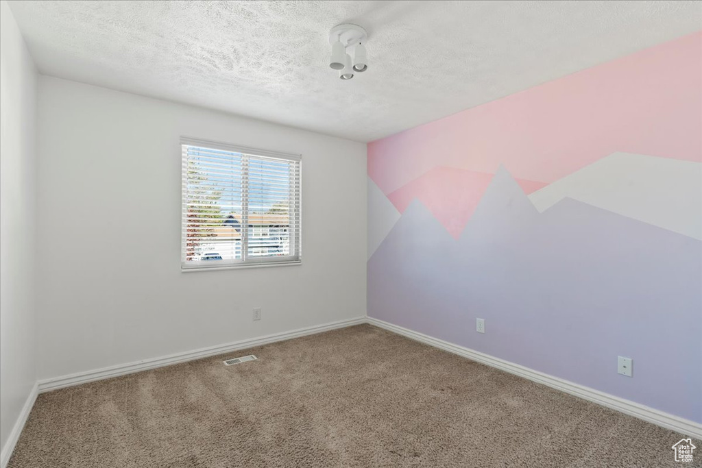 Carpeted empty room with baseboards, a textured ceiling, and visible vents