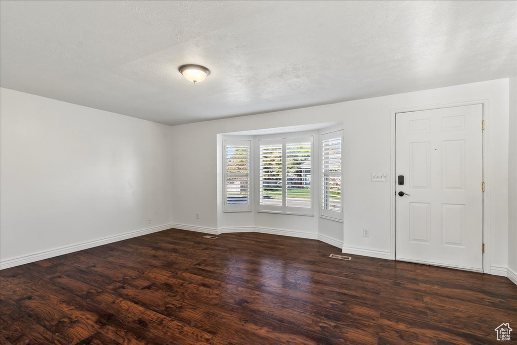 Interior space with dark wood-type flooring, baseboards, and visible vents