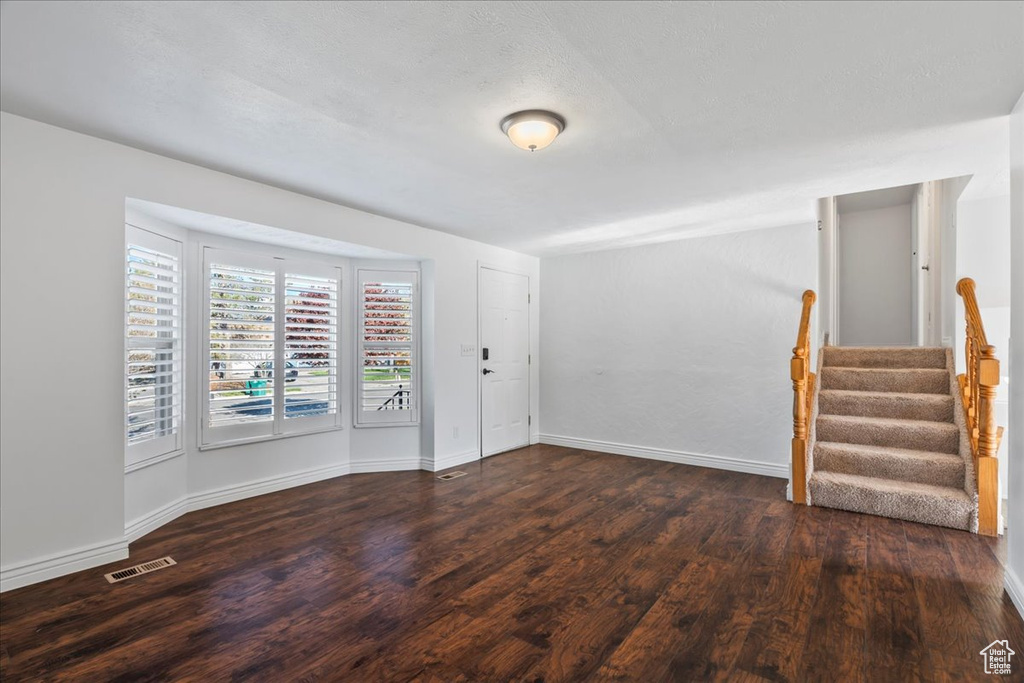 Unfurnished room with stairs, baseboards, visible vents, and wood finished floors