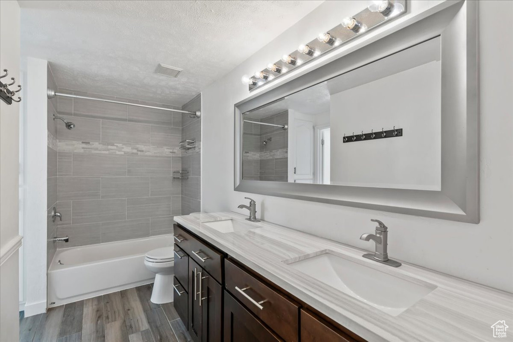 Full bathroom featuring a sink, a textured ceiling, wood finished floors, and toilet