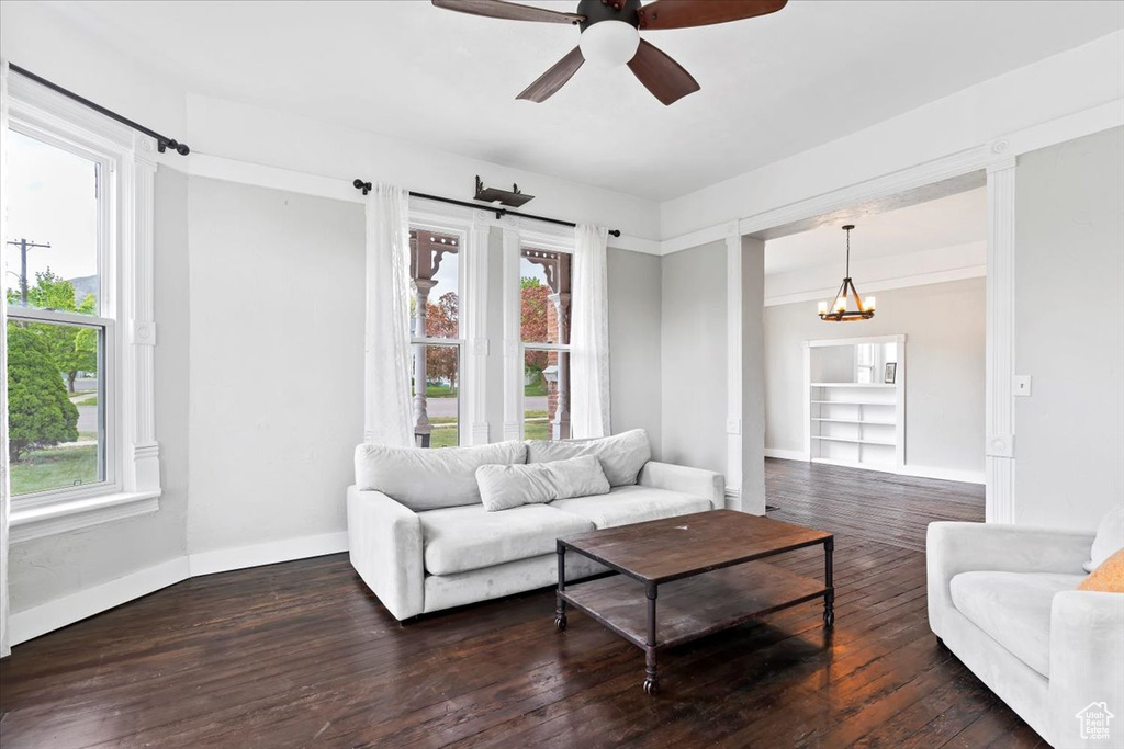 Living room with baseboards, ceiling fan with notable chandelier, and hardwood / wood-style floors