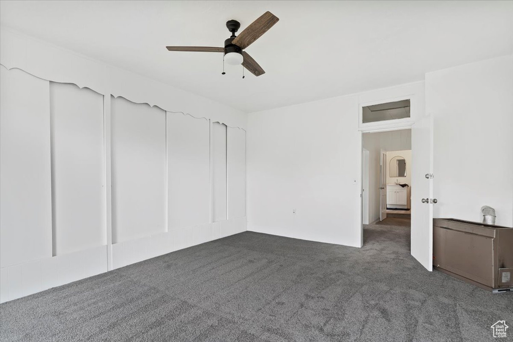 Interior space featuring dark colored carpet and a ceiling fan