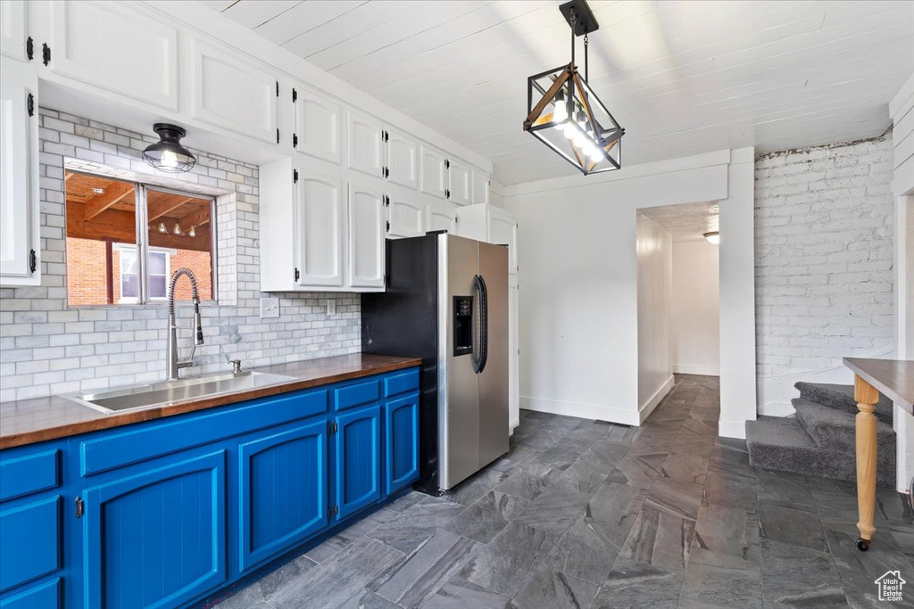 Kitchen featuring a sink, stainless steel fridge with ice dispenser, white cabinets, and blue cabinetry