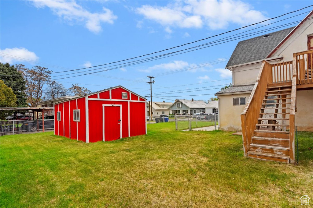 View of yard with an outdoor structure, a deck, a fenced backyard, a storage shed, and stairway