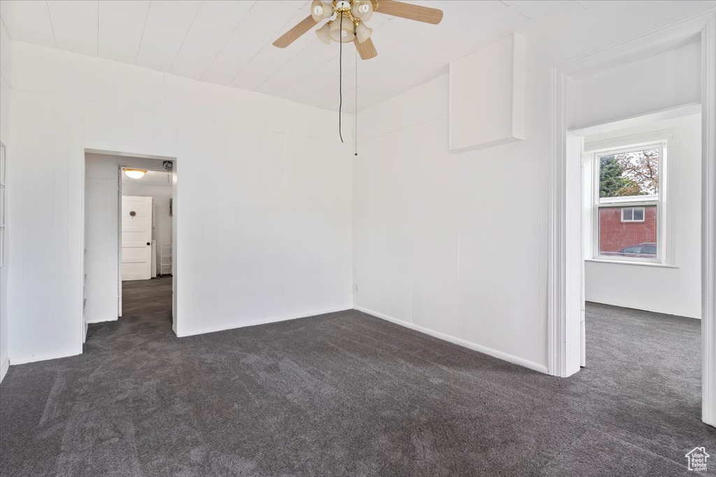 Spare room featuring dark carpet and a ceiling fan