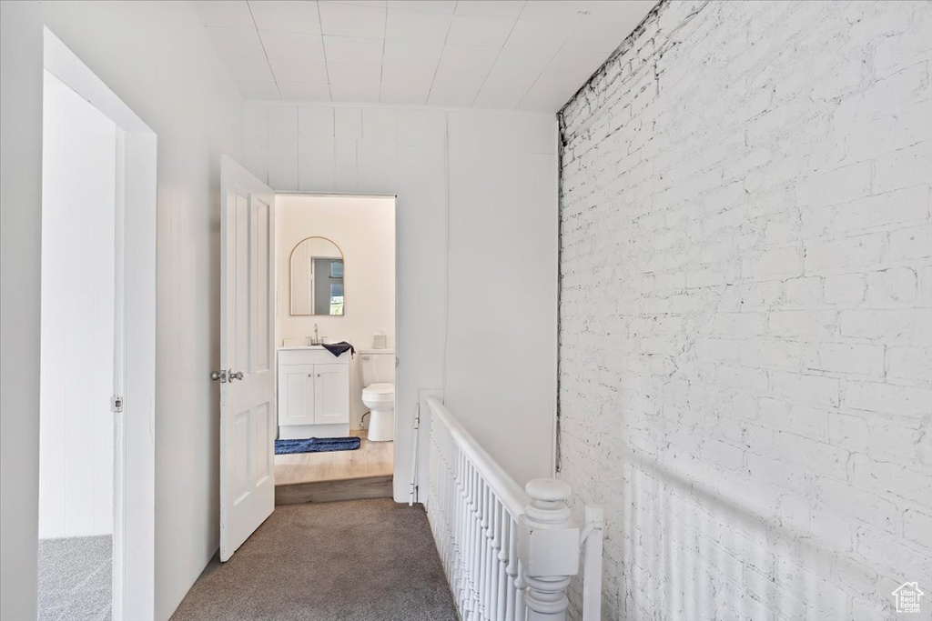 Hallway with a sink, dark carpet, and an upstairs landing