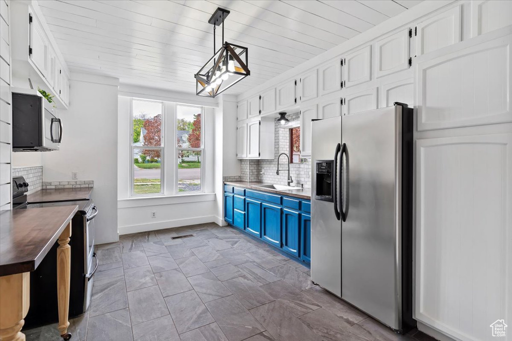 Kitchen with white cabinetry, appliances with stainless steel finishes, a sink, and tasteful backsplash