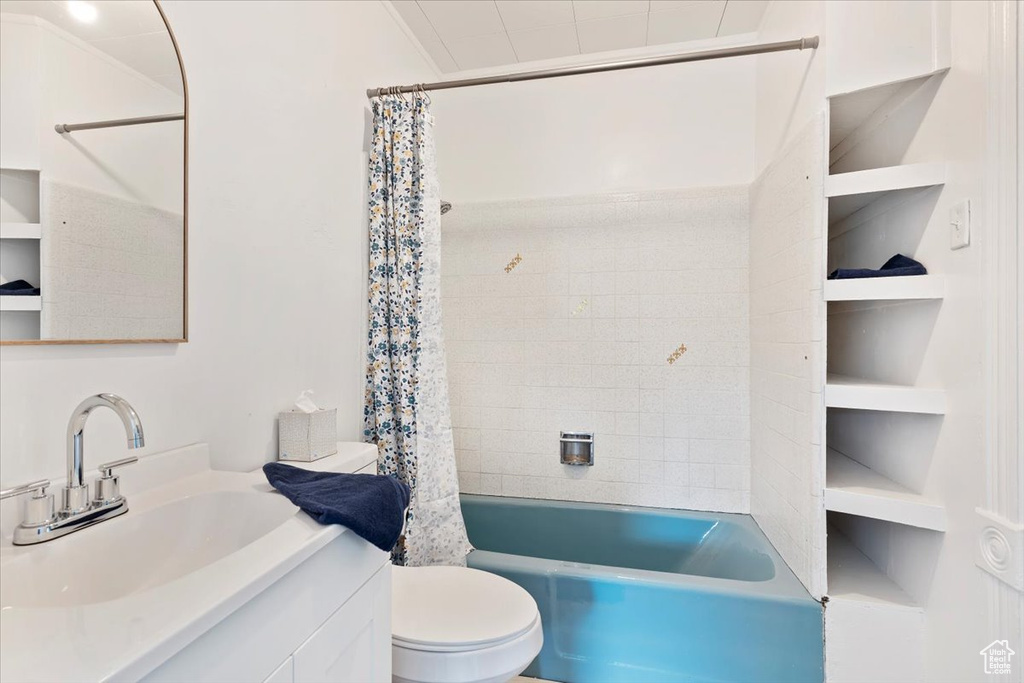 Bathroom featuring vanity, shower / bathtub combination with curtain, and toilet