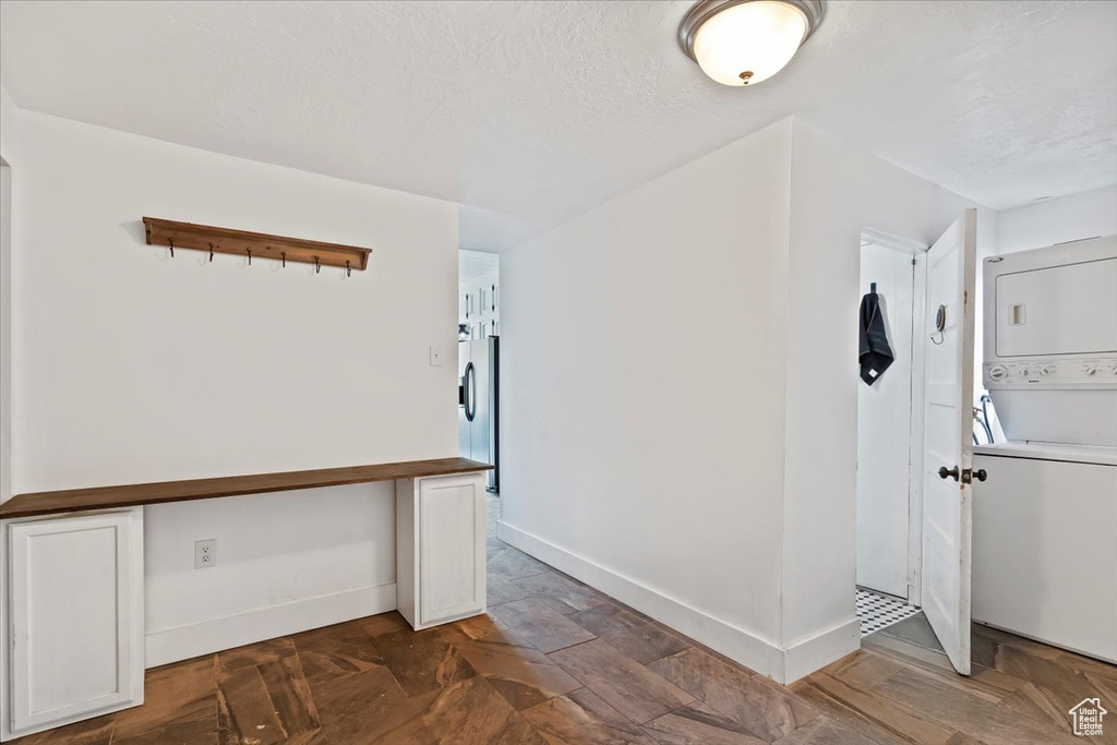 Entryway with stacked washer and dryer, baseboards, and a textured ceiling
