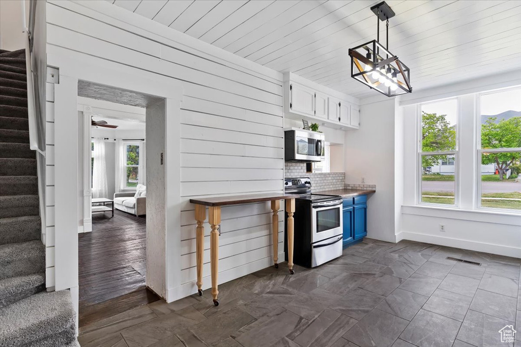 Kitchen with visible vents, baseboards, white cabinets, appliances with stainless steel finishes, and blue cabinetry