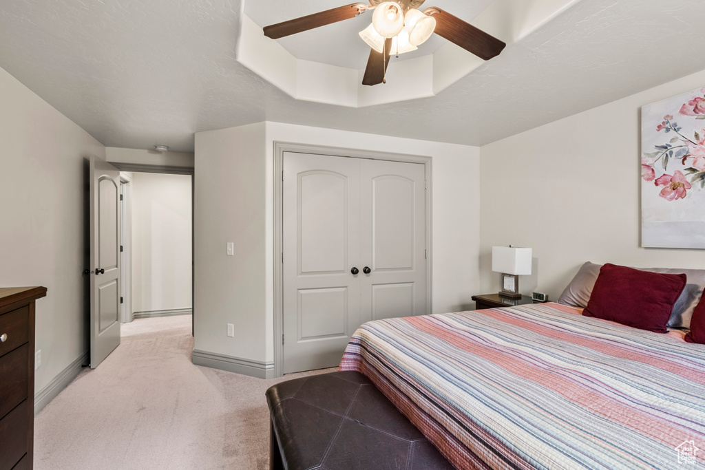 Bedroom with baseboards, ceiling fan, light carpet, and a closet