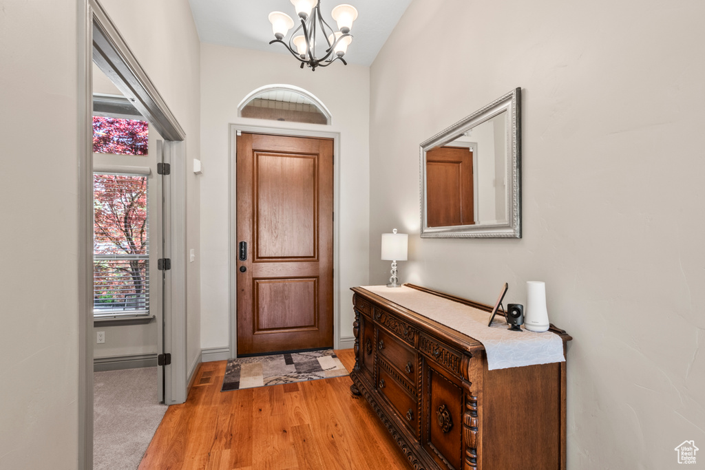 Foyer featuring an inviting chandelier, light wood-style flooring, and baseboards