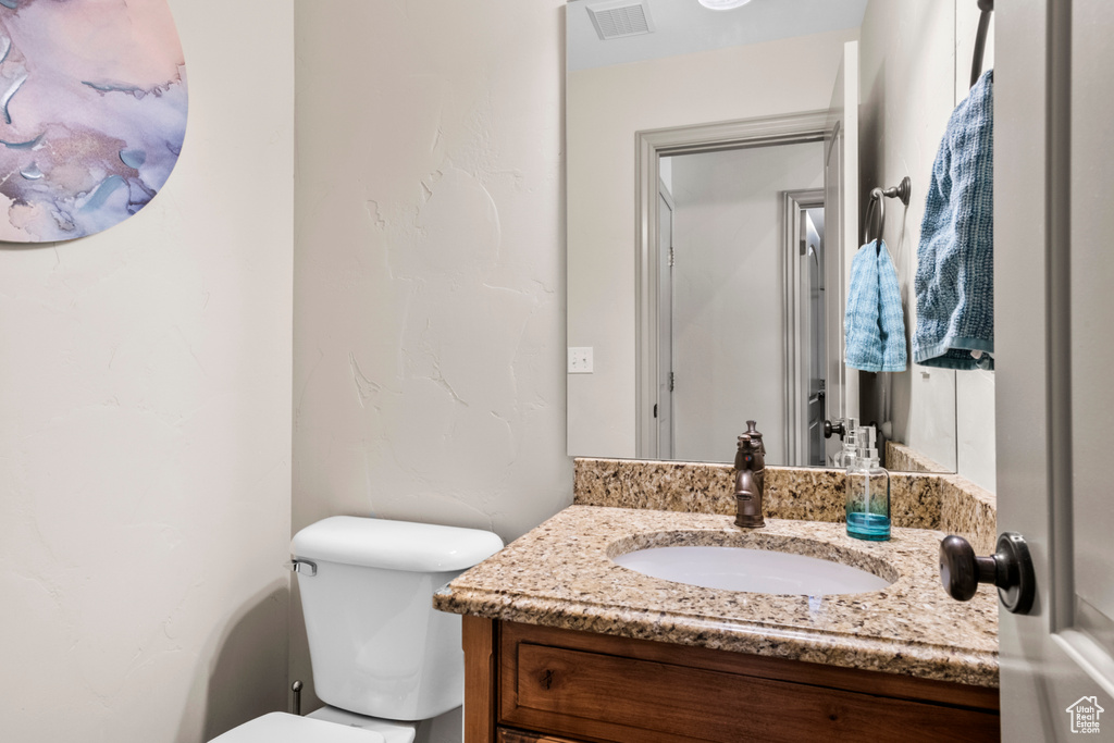 Bathroom featuring vanity, toilet, and visible vents
