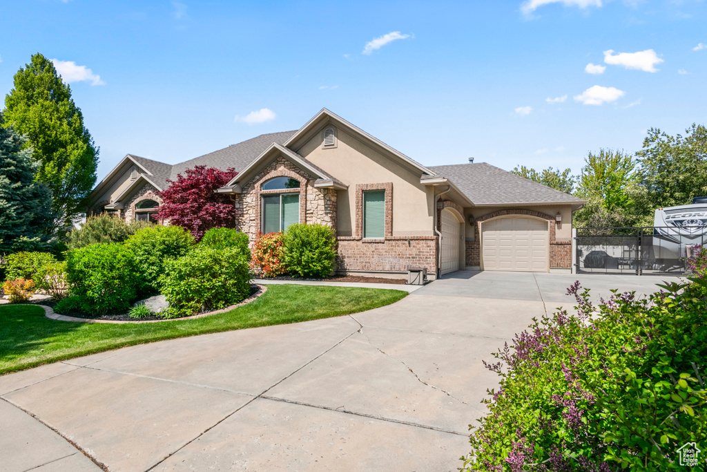 Single story home with fence, an attached garage, brick siding, stucco siding, and concrete driveway