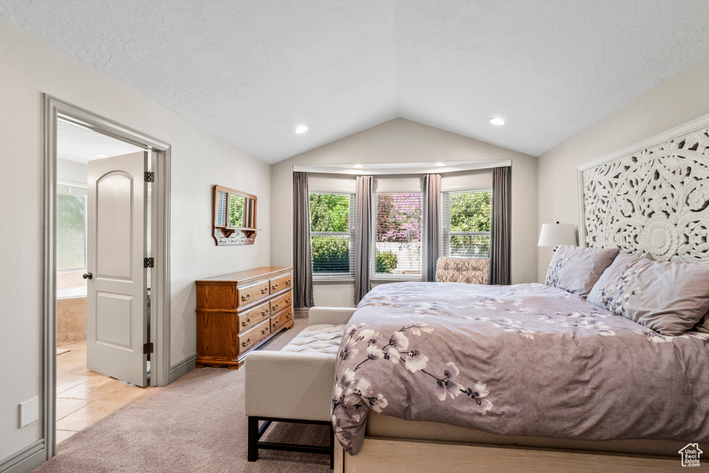Bedroom featuring connected bathroom, light colored carpet, baseboards, and vaulted ceiling