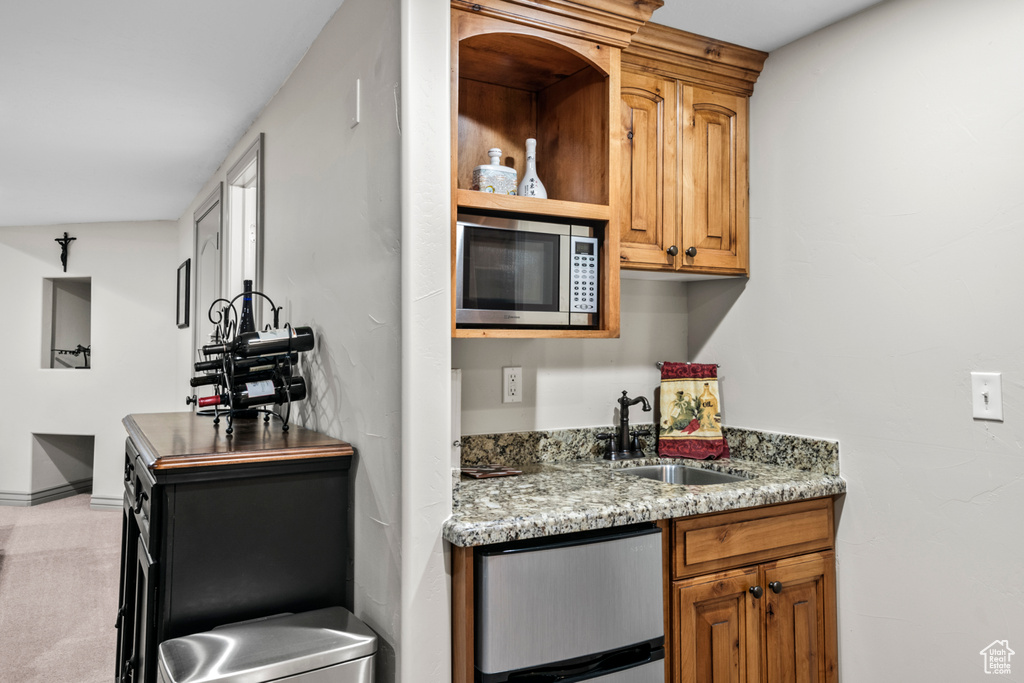Bar featuring baseboards, a sink, stainless steel microwave, and fridge