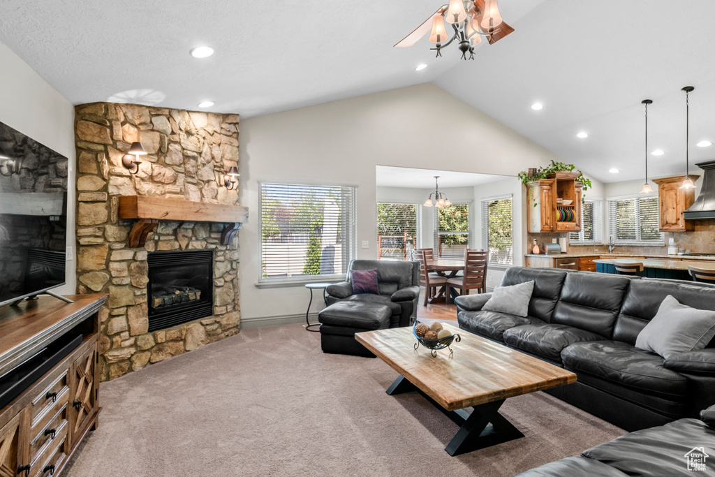 Living area with light carpet, a stone fireplace, high vaulted ceiling, recessed lighting, and a ceiling fan