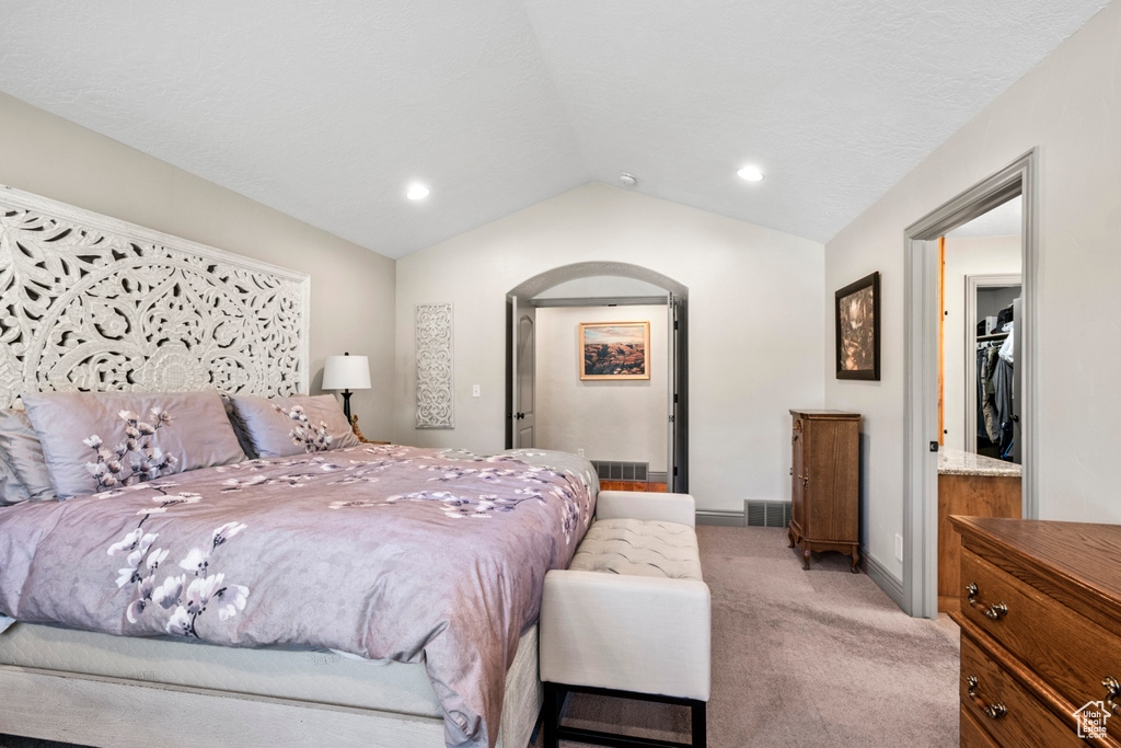Bedroom with light colored carpet, arched walkways, baseboards, lofted ceiling, and recessed lighting