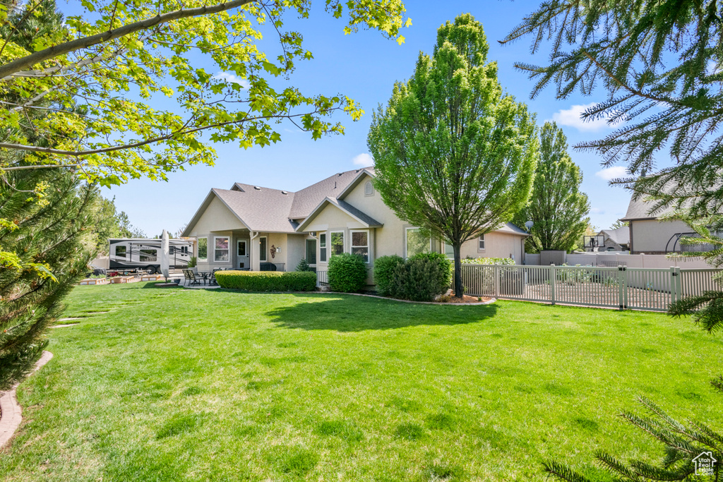 Back of property with a lawn, fence, and stucco siding