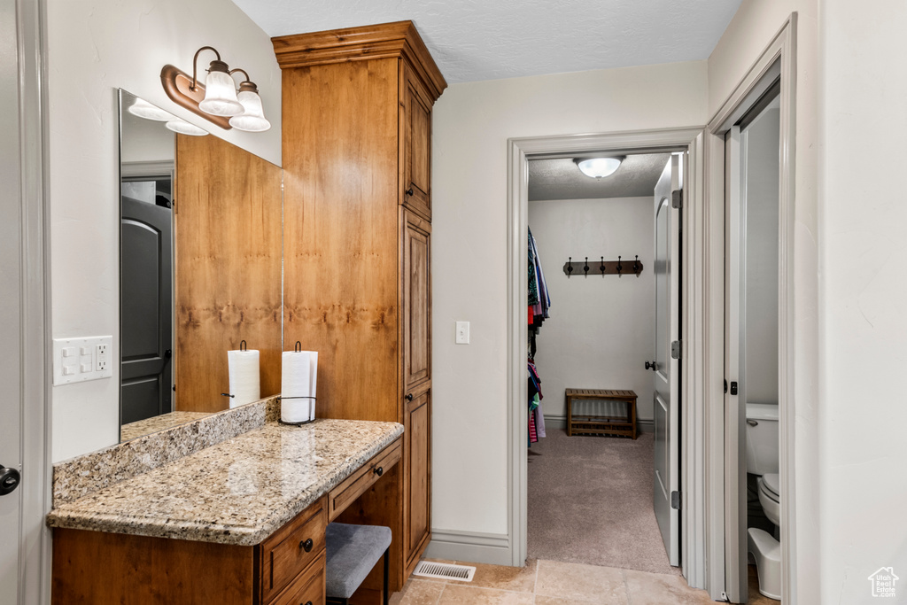 Bathroom featuring vanity, tile patterned flooring, visible vents, and toilet