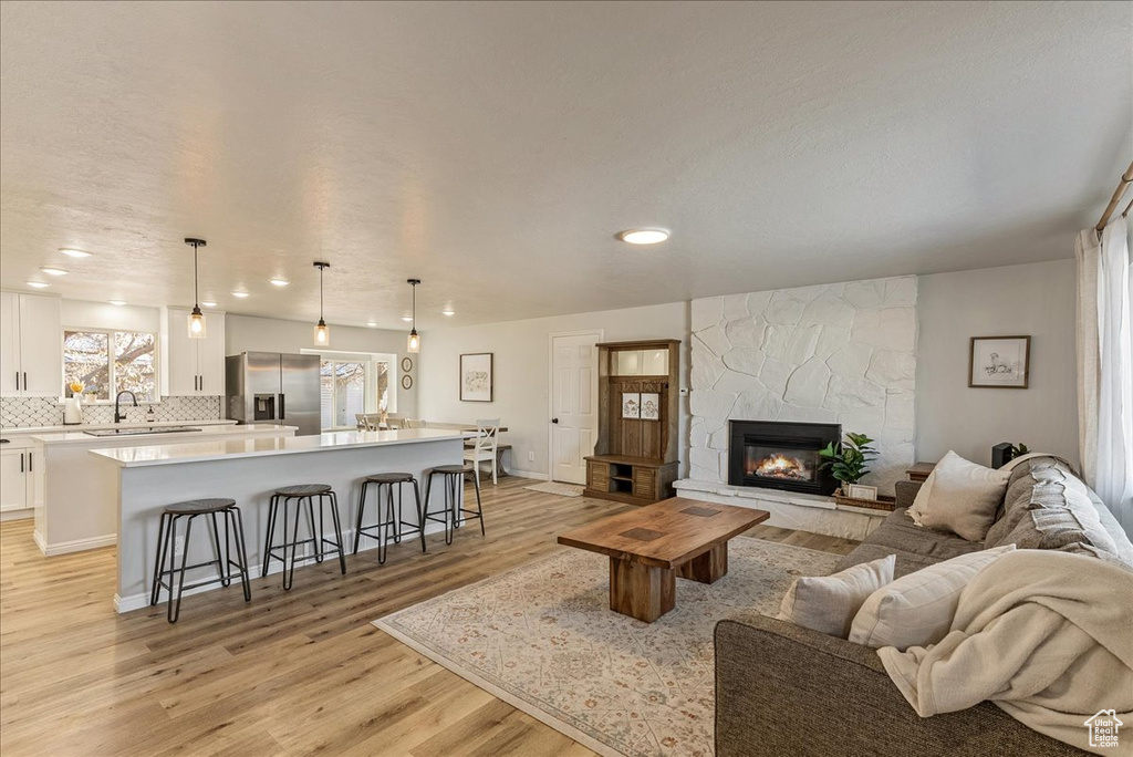 Living room with recessed lighting, light wood finished floors, and a fireplace