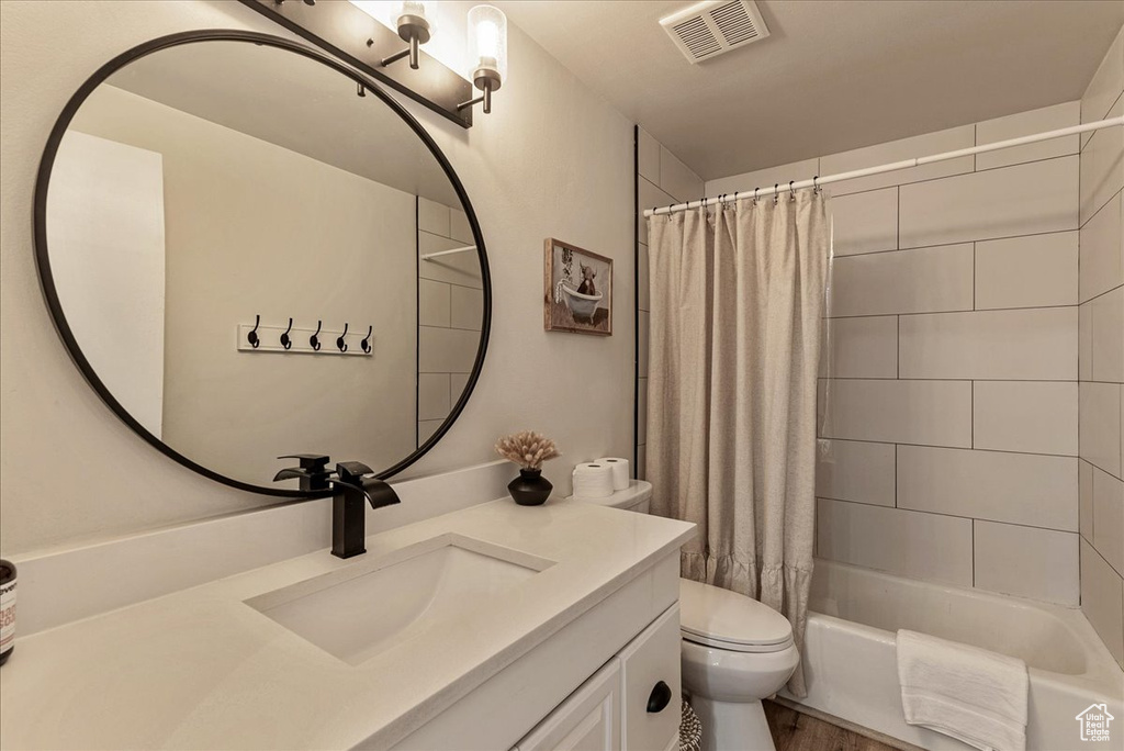 Full bathroom with visible vents, shower / bath combination with curtain, toilet, and vanity