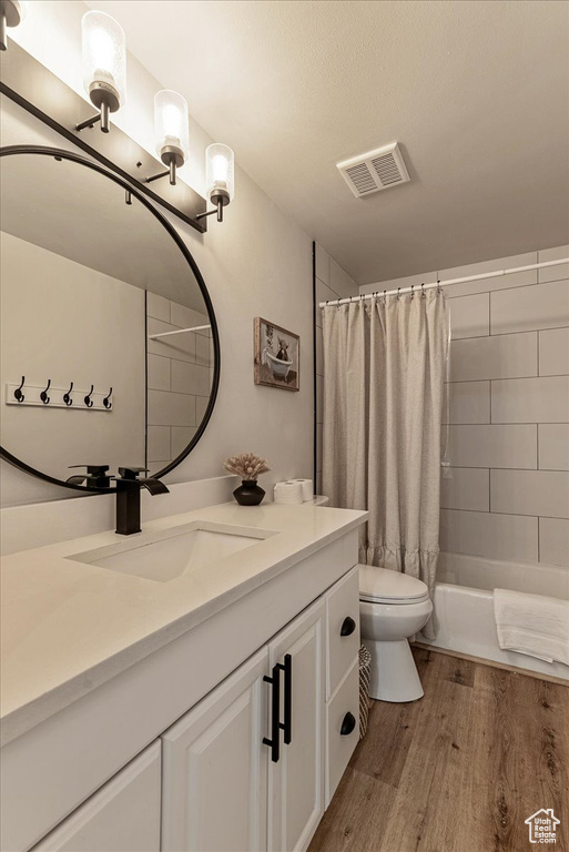Full bath featuring visible vents, wood finished floors, toilet, and vanity