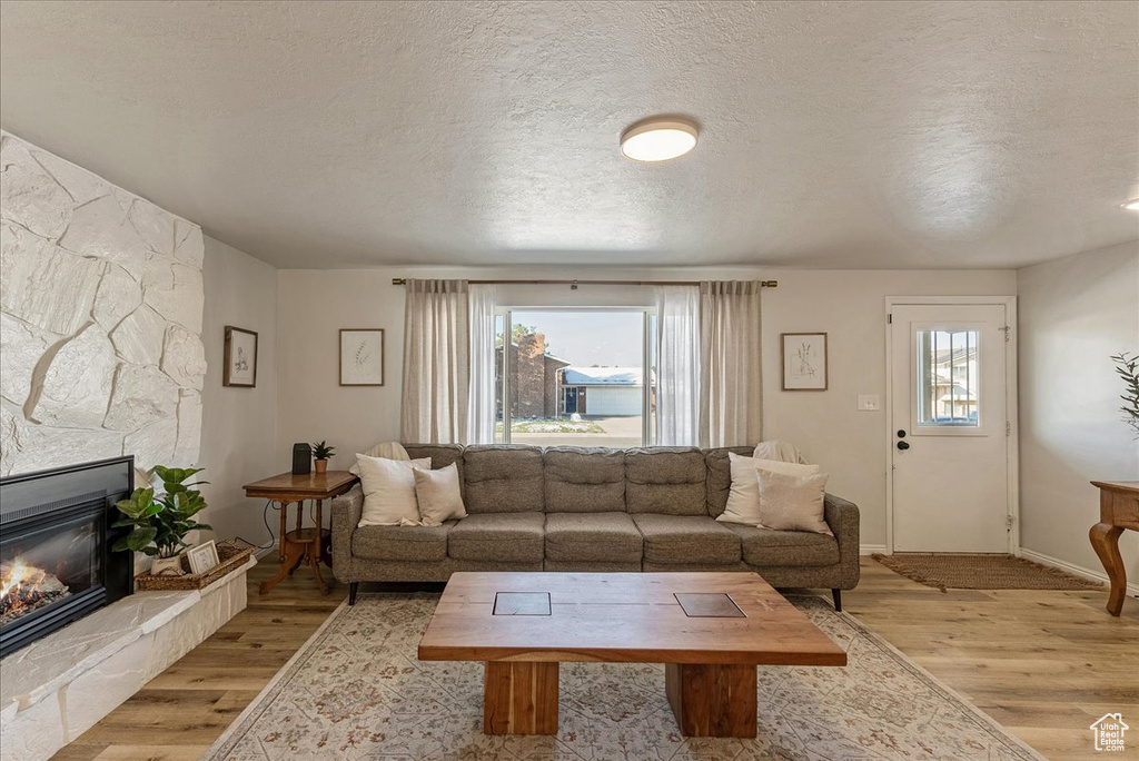 Living area featuring a textured ceiling, light wood finished floors, and a fireplace