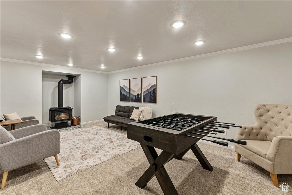 Rec room featuring a wood stove, carpet floors, baseboards, ornamental molding, and recessed lighting