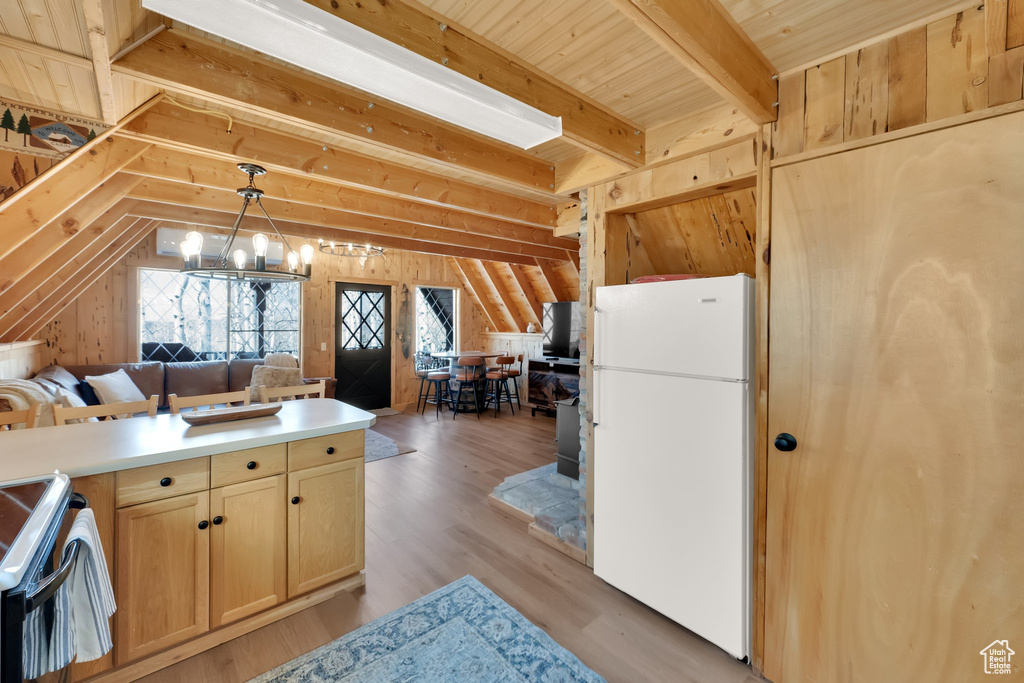 Kitchen featuring wood walls, freestanding refrigerator, open floor plan, an inviting chandelier, and light brown cabinets