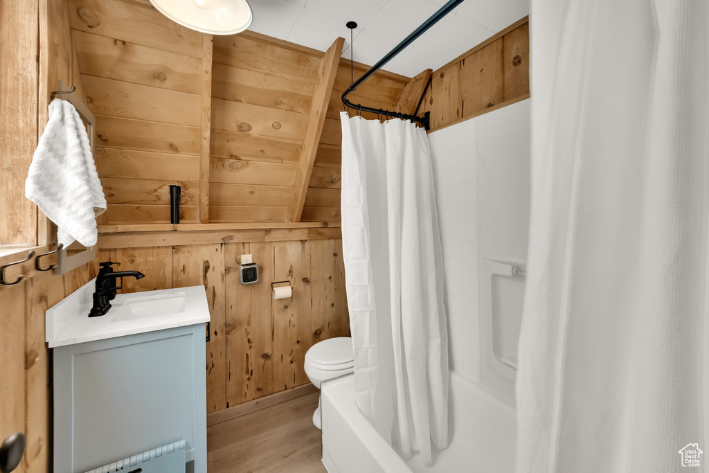Full bathroom featuring vanity, wood walls, wood finished floors, toilet, and radiator heating unit